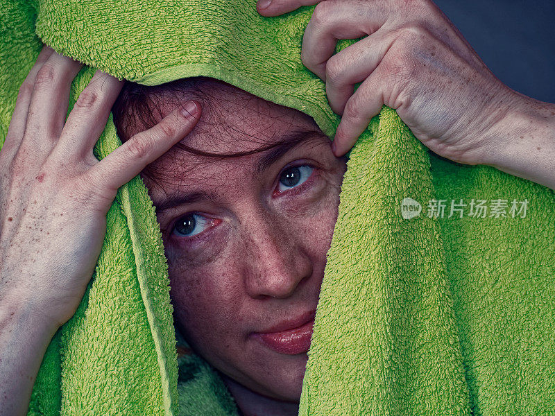 一个女人正在用绿色的毛巾擦头发
