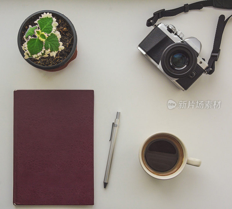 俯视图的相机，记事本，钢笔，花和咖啡杯