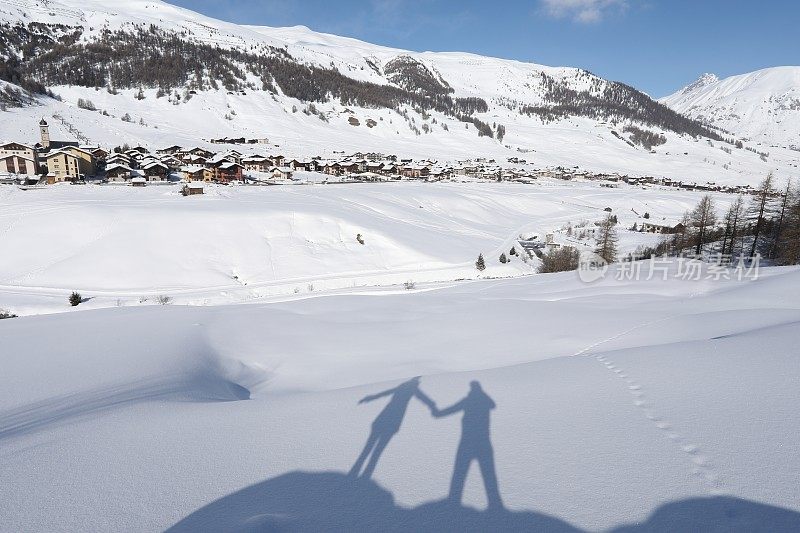 一对夫妇的影子在深雪上面的山谷。