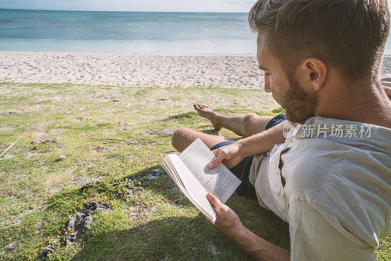 一个年轻人正在热带海滩上看书