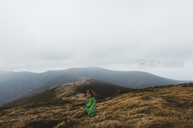 幸福的女人在山里遇到早晨跑步带着睡袋