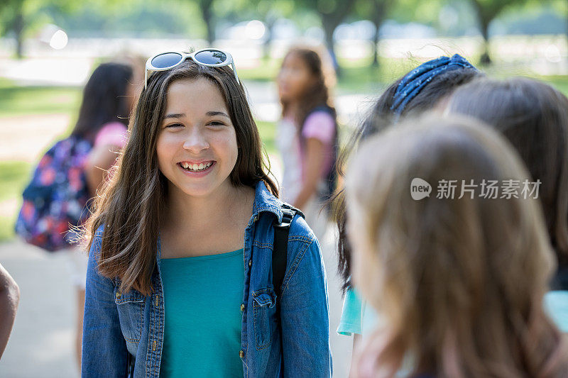 阳光明媚的日子里，十几岁的孩子和同学们站在学校外面