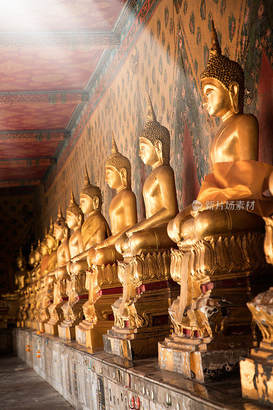 在曼谷的佛教寺庙里，闪闪发光的金色佛像排成一排