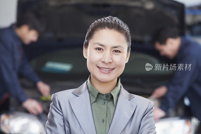 微笑的中国妇女在汽车修理店