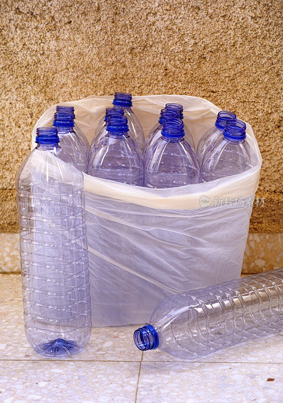 石头墙附近的塑料袋里装着空塑料瓶。