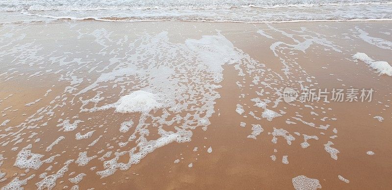 泡沫状的白色海浪拍打着海滩