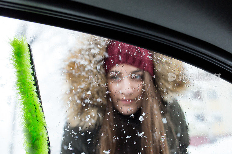 年轻女子正在清理车窗上的雪