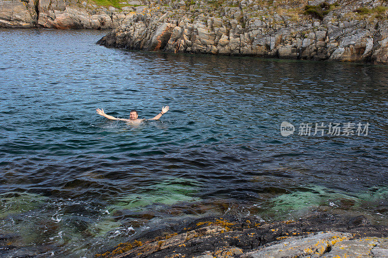 一名男子双手举在挪威海的水里