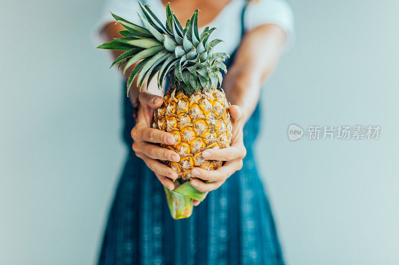 年轻女子拿着菠萝，近距离的水果