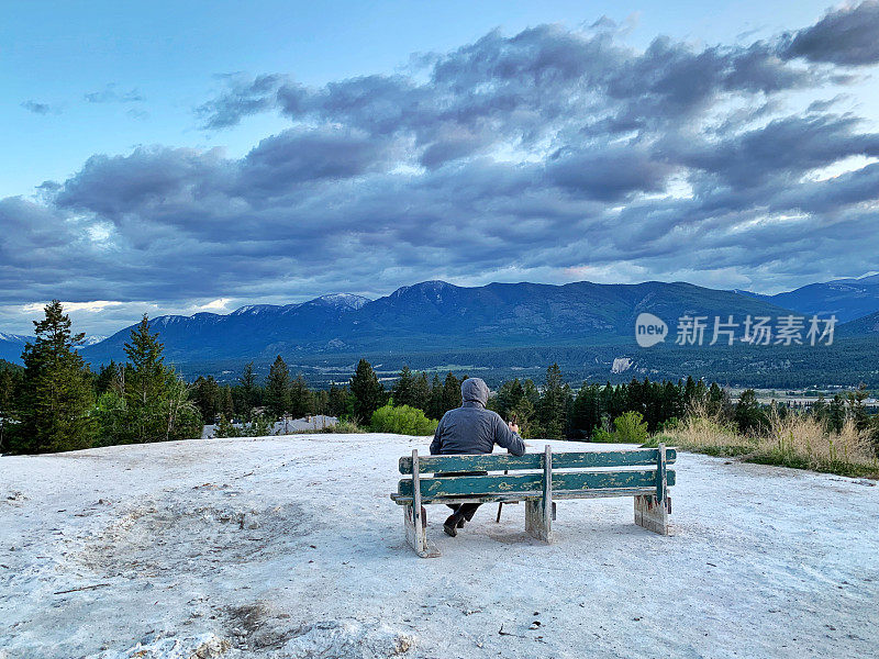 一位老人坐在长凳上欣赏风景