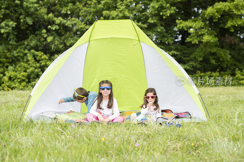 孩子们坐在帐篷里享受大自然。