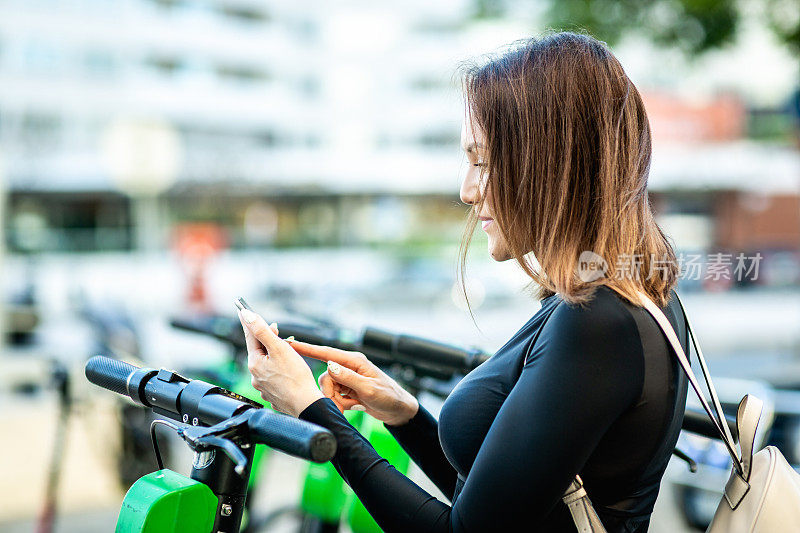 一名女子用手机应用程序解锁一辆电动滑板车