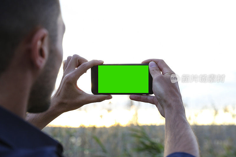 一名男子用绿屏智能手机拍照