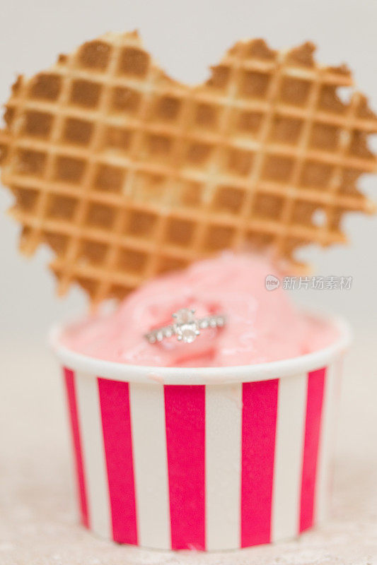 粉色冰淇淋杯上的椭圆形钻石订婚戒指