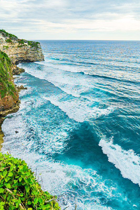 Uluwatu巴厘岛。蓝色的海洋和岩石山，覆盖着热带树木。