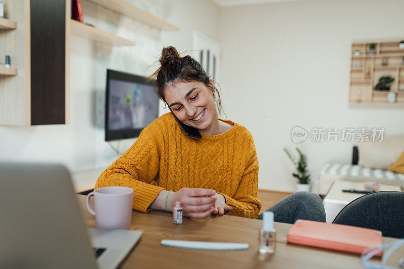 一名年轻女子在冠状病毒隔离期间一边修指甲一边打电话