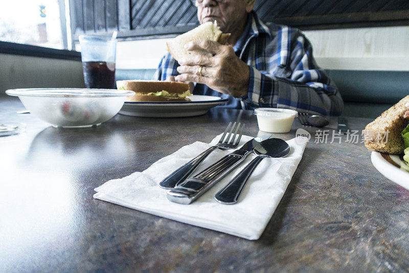 老人在餐厅享用鸡蛋沙拉三明治午餐