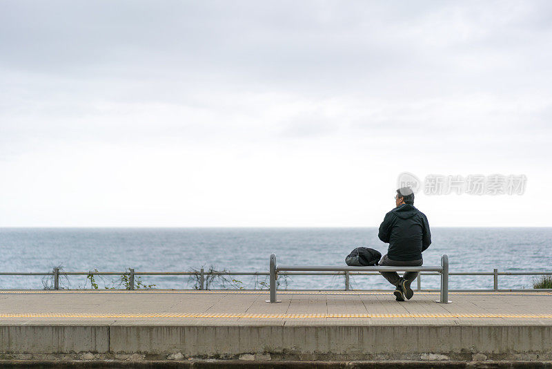 背包老人游客在海边等火车