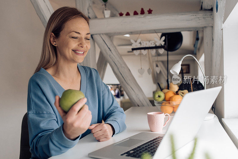 快乐的女人，一边吃苹果，一边在家上网