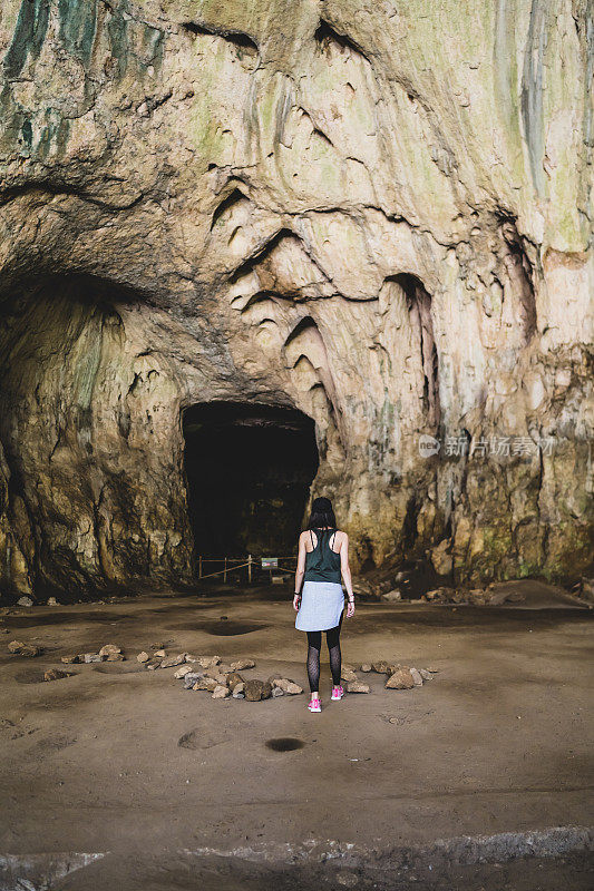 女孩站在洛维奇附近的德维塔什卡洞穴前