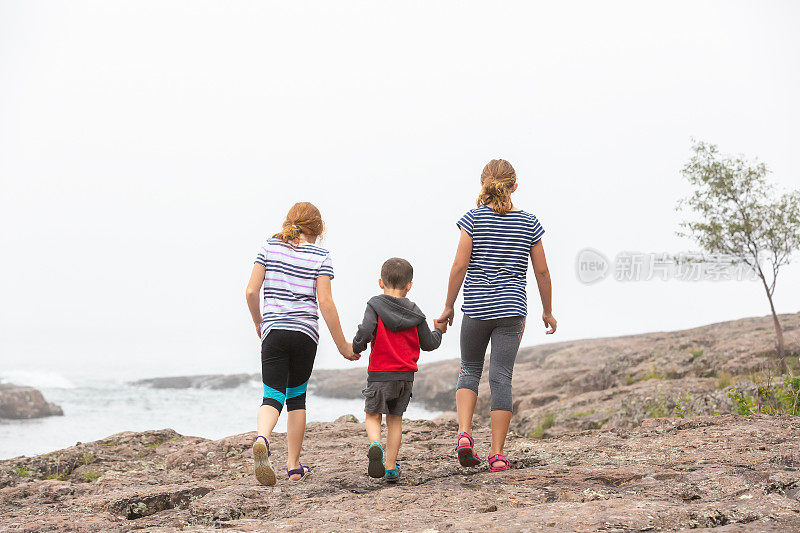 3个孩子在雾天沿着苏必利尔湖海岸散步