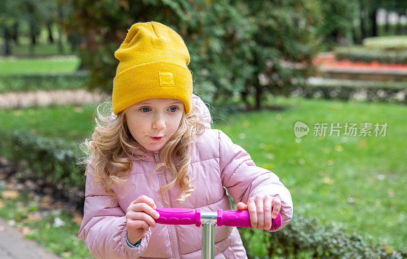 小女孩在公园里骑踏板车。