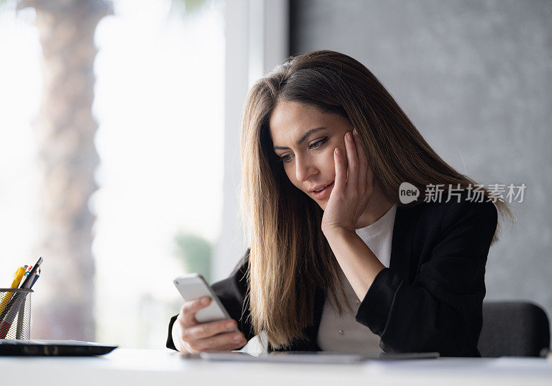 年轻快乐的女商人在办公室里用电话