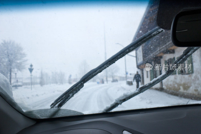 在大雪中驾车穿过阿尔卑斯山的一个村庄