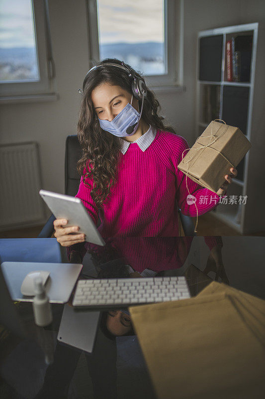 年轻女子戴着防护口罩，在平板电脑上进行视频通话，推广新产品，并在网上商店工作