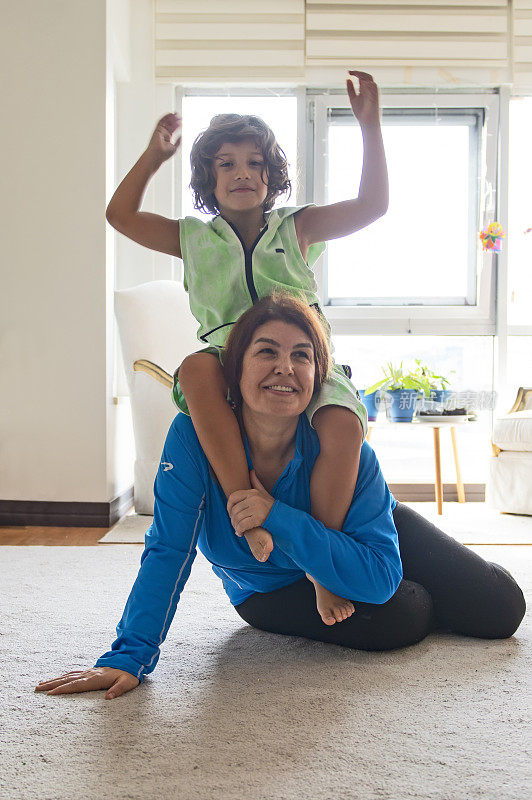 年轻的母亲和她的儿子锻炼普拉提，瑜伽，健身和一只猫在家里