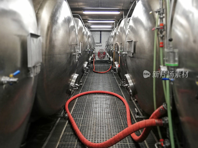 酿酒厂的酒窖里有一排装着成熟啤酒的储罐和管道