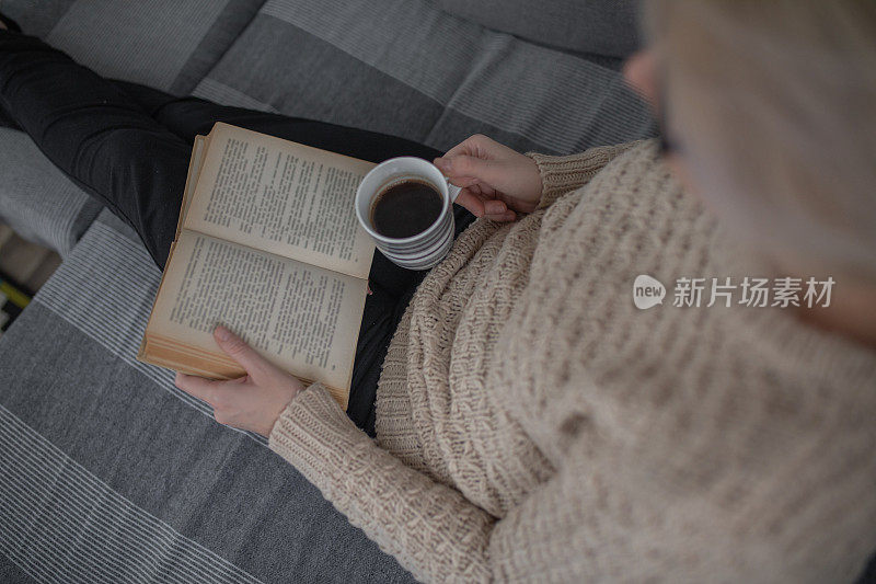特写的女人在家里看书和拿着一杯咖啡
