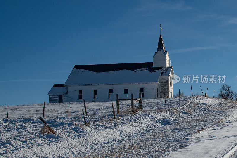 旧的废弃的教堂在白雪覆盖的小山和白雪覆盖的道路