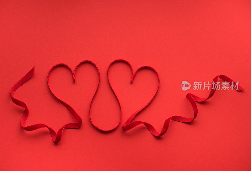 两颗用红丝带织成的红心。情人节贺卡