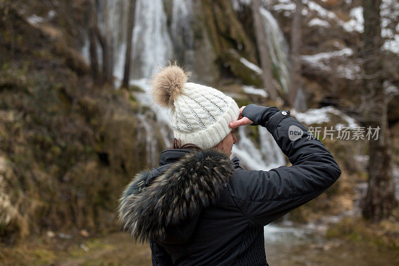 美丽的女人徒步旅行者站在森林小径和看别处。女性背包徒步在大自然