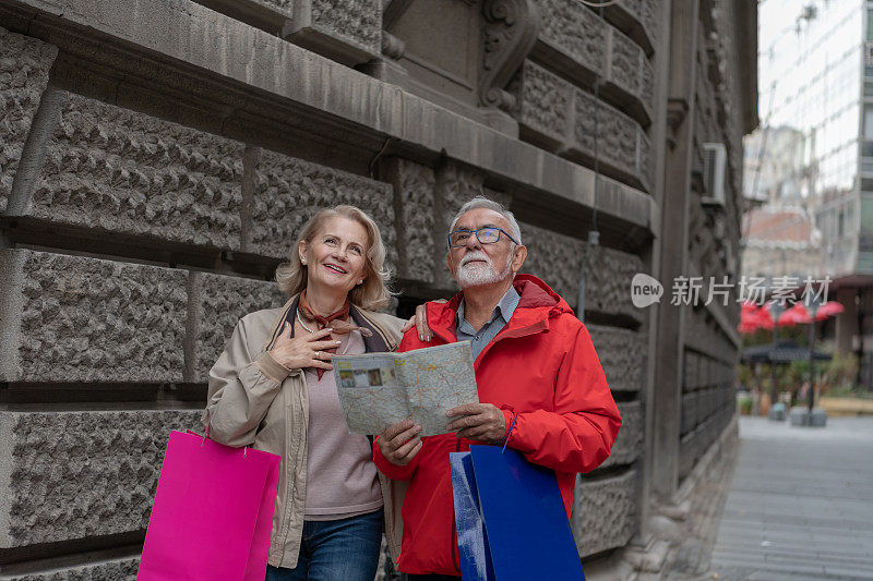 老人和他的妻子带着旅游地图在市区散步。