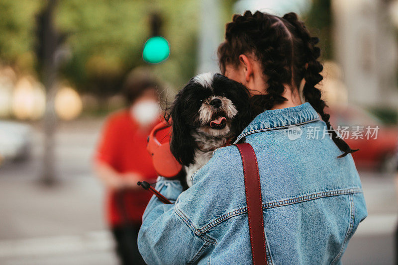 一个年轻女子在城市的街道上遛狗