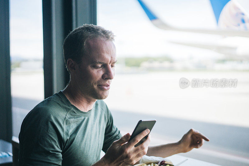 一名年轻人在机场用餐时查看手机