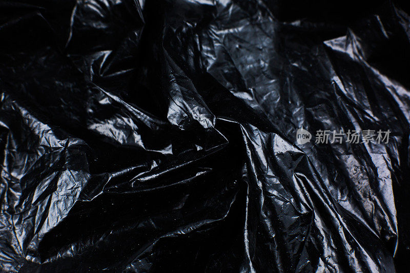 皱巴巴的黑色塑料袋纹理背景。光滑的聚乙烯覆盖