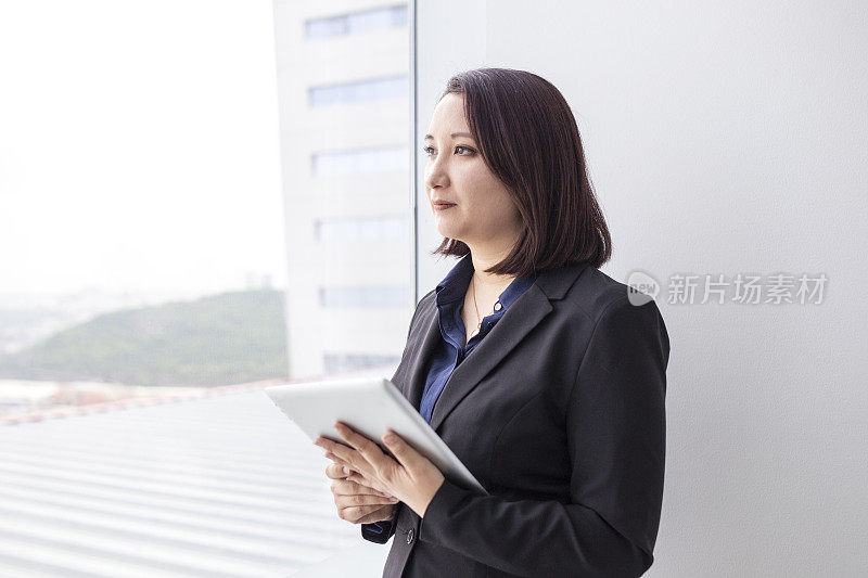 一个日本女人从办公室的窗户往外看