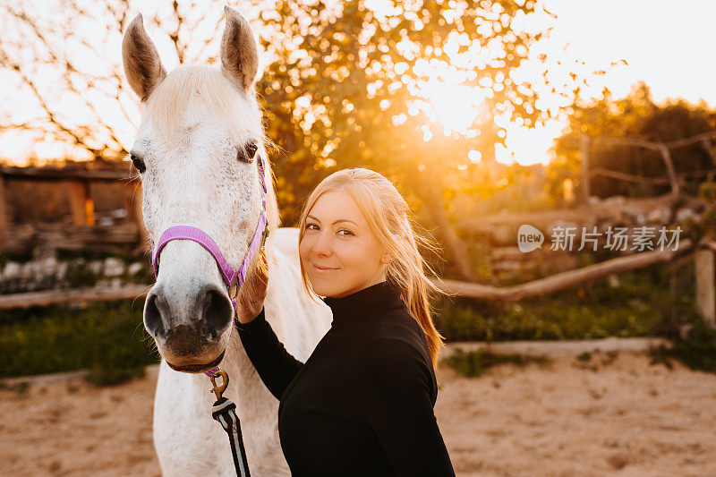 在马略卡岛的一个乡村马厩里，一个金发少女和她的白色母马之间的友谊的美丽肖像