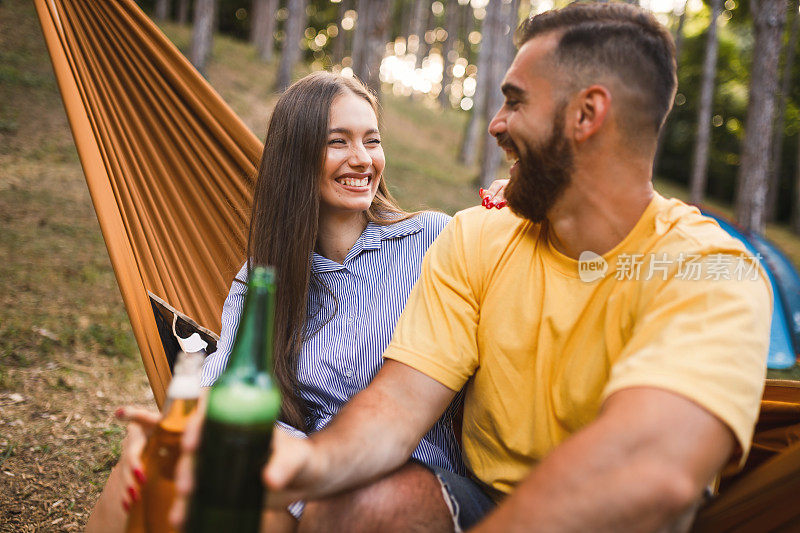 情侣旅行者放松，干杯，喝啤酒，聊天。快乐的人们喜欢喝酒和在大自然中露营