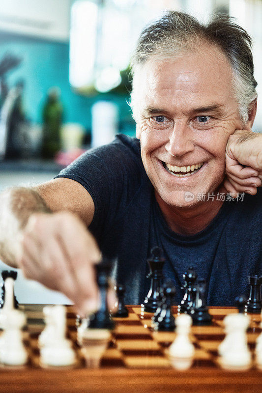 英俊的男子在家里的一张桌子上下棋，当他做出了获胜的一步时，他变得兴奋起来