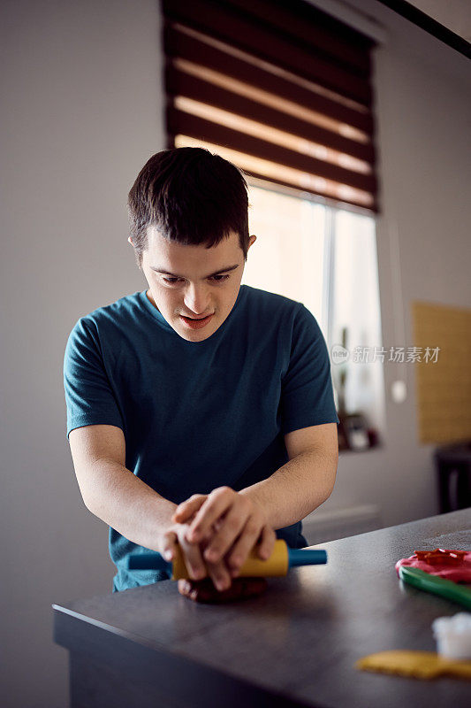 一个患有唐氏综合症的年轻人在家用模塑粘土。
