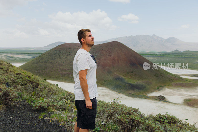 一名男性游客在土耳其的山顶上欣赏红色火山口的景色