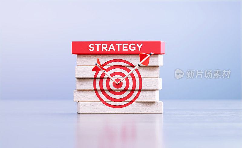 战略概念-箭命中靶心目标符号和战略字木块在前面离焦背景