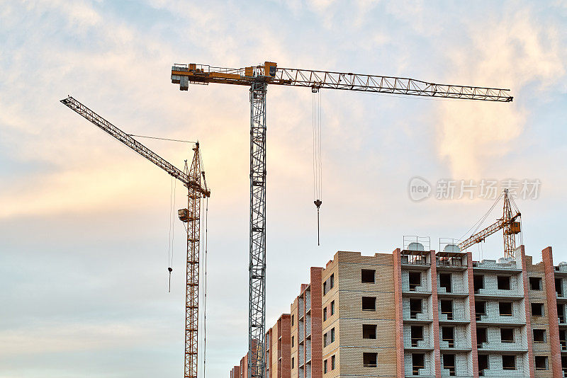 建筑工地上的塔吊和建筑物在傍晚黄蓝色天空的日落背景