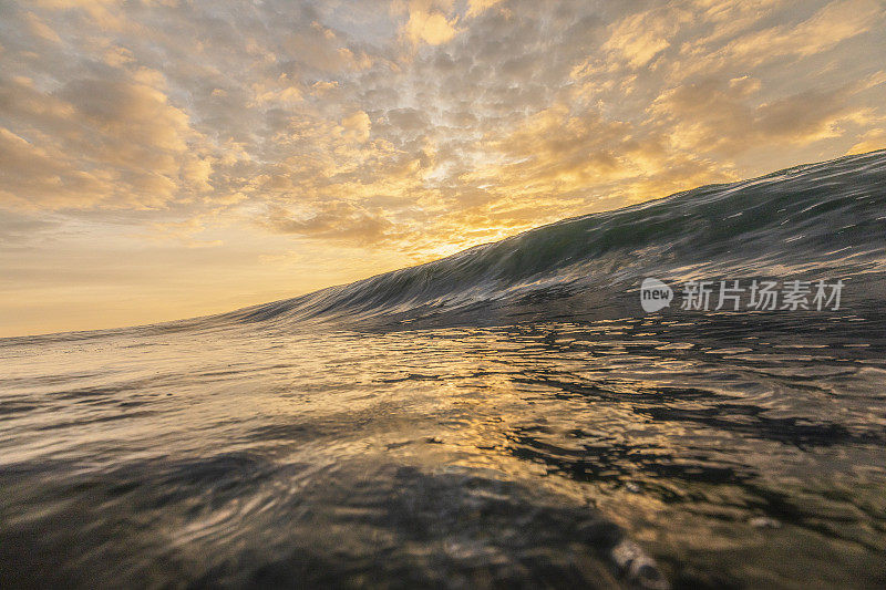 明亮的金色日落反射在海洋与大波浪形成
