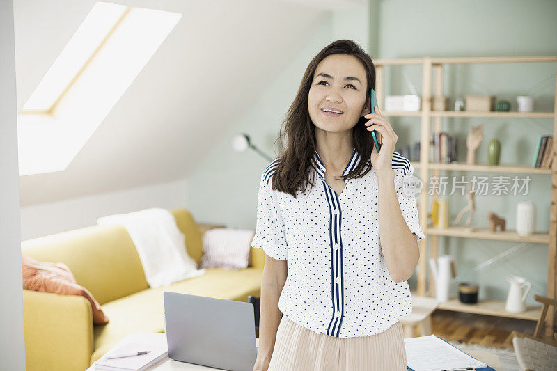 亚洲女商人在家里打商务电话