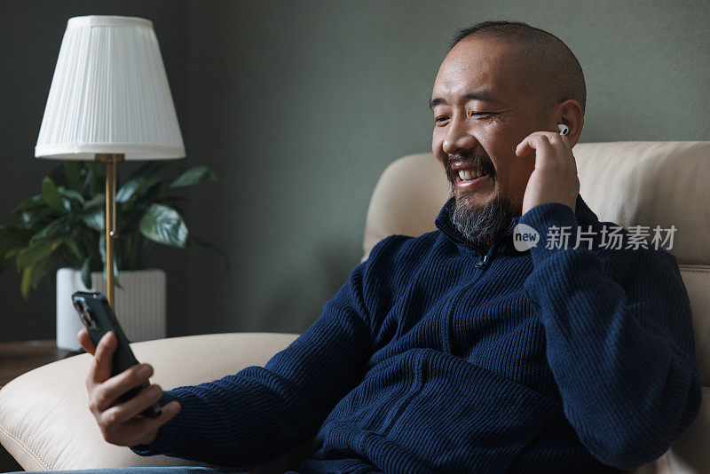 一名亚洲中年男子开心地用手机听音乐